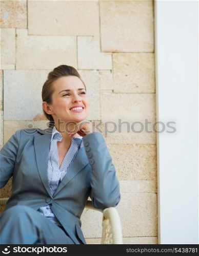 Happy business woman sitting on terrace with mobile phone