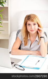 happy business woman sitting, thinking and working on laptop computer at office