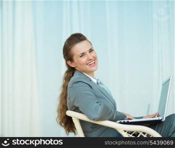 Happy business woman sitting with laptop