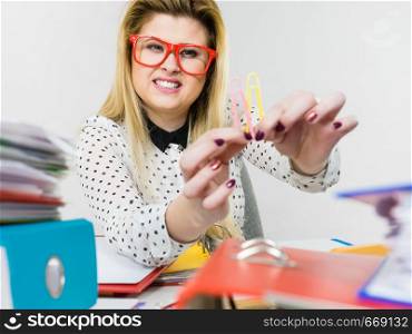 Happy business woman sitting working at desk full off documents in binders showing paper clips. Happy business woman in office