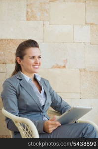 Happy business woman with tablet pc sitting on terrace