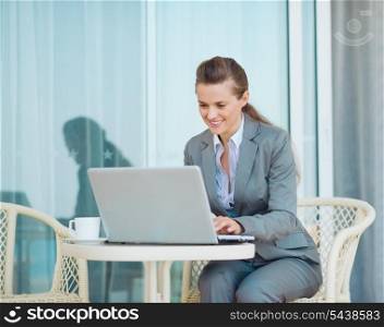 Happy business woman working with laptop on terrace