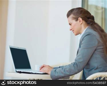 Happy business woman working with laptop on terrace