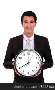Happy businessman holding large clock
