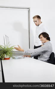 Happy businessman showing computer screen to coworker at desk