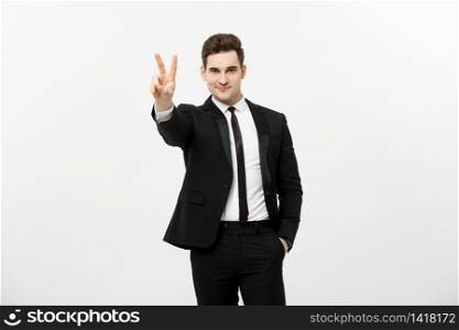 Happy businessman showing two fingers or victory gesture, against grey background. Success in business, job and education concept. Blank copyspace area for advertisiment, slogan or text.. Happy businessman showing two fingers or victory gesture, against grey background. Success in business, job and education concept. Blank copyspace area for advertisiment, slogan or text