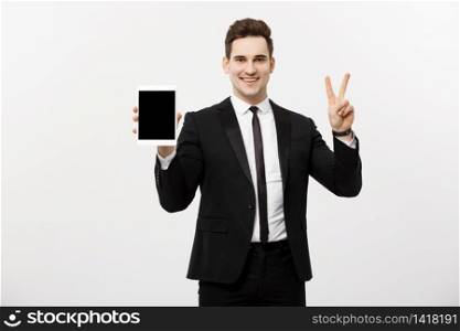 Happy businessman showing two fingers or victory gesture holding tablet, against grey background. Success in business, job and education concept. Blank copyspace area for advertisiment, slogan or text.. Happy businessman showing two fingers or victory gesture holding tablet, against grey background. Success in business, job and education concept. Blank copyspace area for advertisiment, slogan or text
