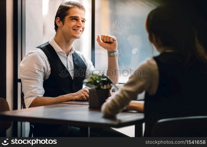 Happy Businessman Smiling while Meeting with his Partnership or Teamwork in Cafe or Creative Workplace. Relaxing and Comfortable Posture