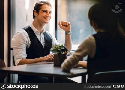 Happy Businessman Smiling while Meeting with his Partnership or Teamwork in Cafe or Creative Workplace. Relaxing and Comfortable Posture