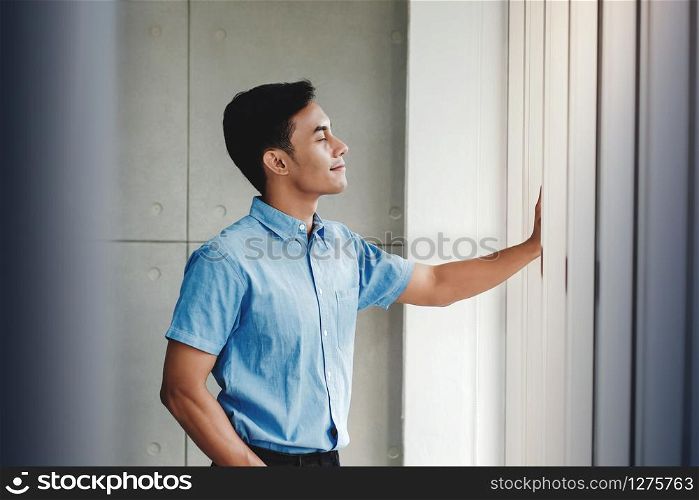 Happy Businessman Standing by the Window in Office. Closed Eyes and Smiling. Keep Calm and Breathing Air to Start a New Day