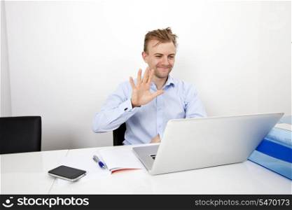 Happy businessman video conferencing on laptop in office
