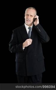 Happy businessman wearing a black suit, worried and preoccupied on mobile phone, on black background