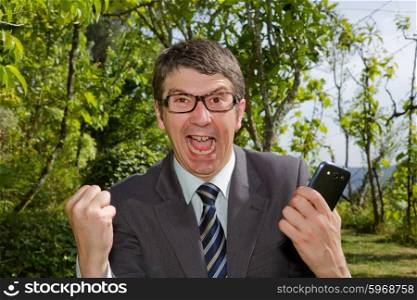Happy businessman winning outdoor with mobile phone