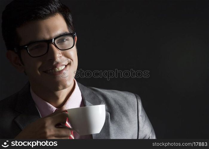 Happy businessman with coffee cup against black background