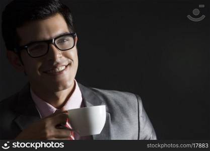 Happy businessman with coffee cup against black background