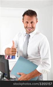 Happy businessman with thumb up in the office