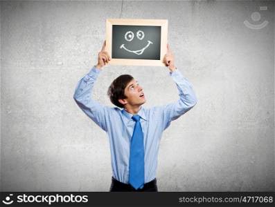 Happy businessman. Young happy businessman holding frame with drawn smile