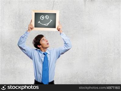 Happy businessman. Young happy businessman holding frame with drawn smile
