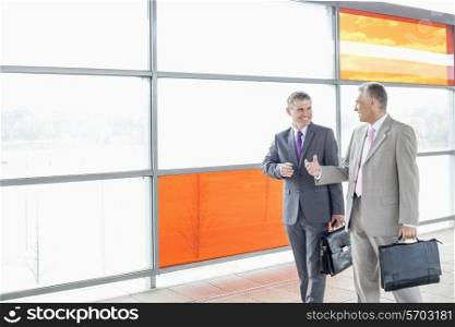 Happy businessmen talking while walking in railroad station