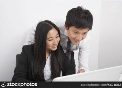 Happy businesspeople discussing over laptop in office