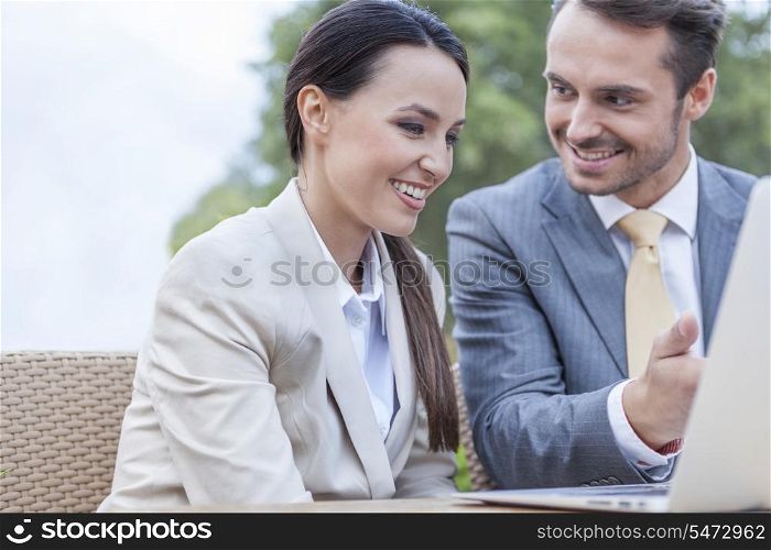 Happy businesspeople discussing over laptop outdoors
