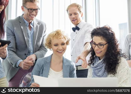 Happy businesspeople working on laptop in creative office