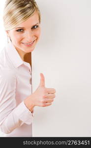 Happy businesswoman behind blank advertising banner thumbs up