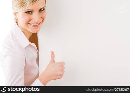 Happy businesswoman behind blank advertising banner thumbs up