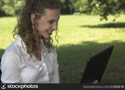 Happy businesswoman enjoying her lunchbreak while working on her computer in the park