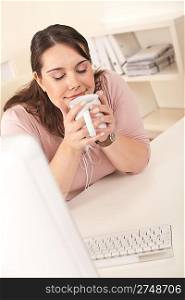 Happy businesswoman having coffee break at office sitting at desk