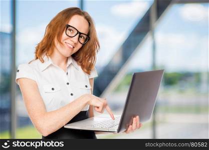 Happy businesswoman presses a button on the laptop in the office