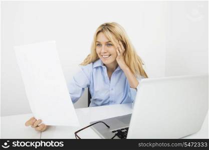 Happy businesswoman reading document in office