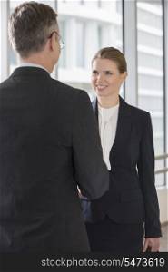 Happy businesswoman shaking hands with businessman in office
