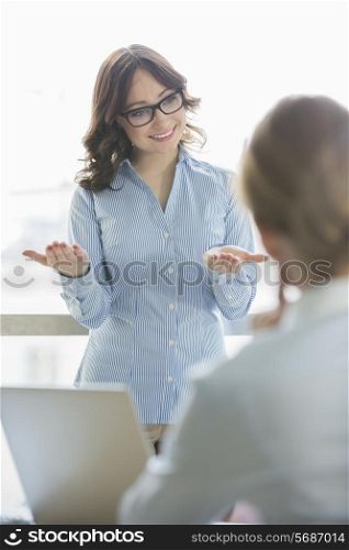 Happy businesswoman talking to businesswoman in office
