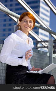happy businesswoman with laptop computer in the city