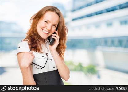 Happy businesswoman with phone in the office
