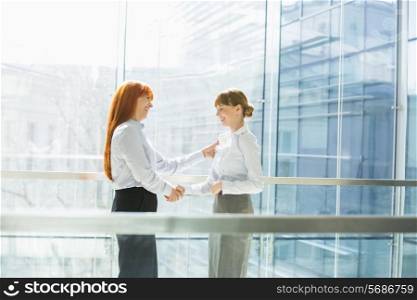 Happy businesswomen shaking hands in office