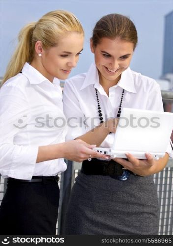 happy businesswomen with laptop computer in the city