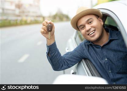Happy buyer holding keys near the car