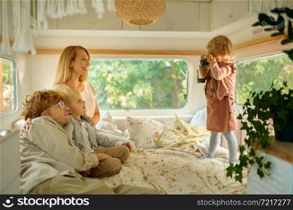 Happy campers family poses in motorhome, summer camping. Couple with children travel in camp car, trailer interior on background. Campsite adventure, travelling lifestyle, vacation on rv car. Happy campers family poses in motorhome, camping