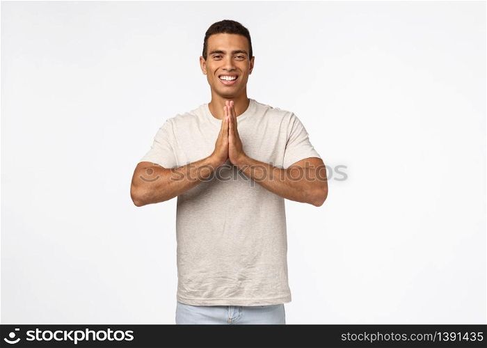 Happy, carefree handsome brazilian man in casual outfit, clasp hands together in pray, namaste gesture smiling joyfully, send positive vibes, begging favor or help, thanking friend, white background.. Happy, carefree handsome brazilian man in casual outfit, clasp hands together in pray, namaste gesture smiling joyfully, send positive vibes, begging favor or help, thanking friend, white background