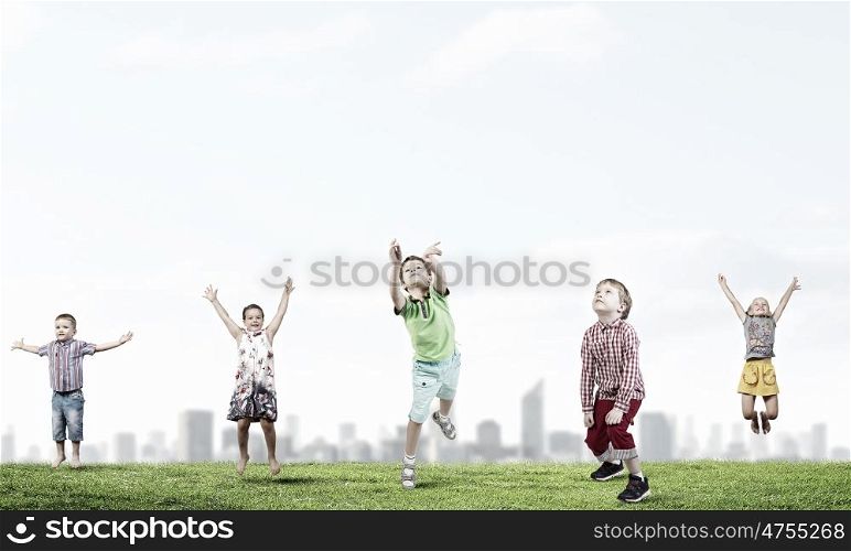 Happy careless childhood. Group of children jumping high in sky joyfully
