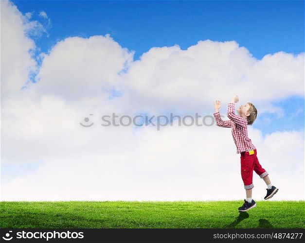 Happy careless childhood. Little happy cute boy catching sun in sky