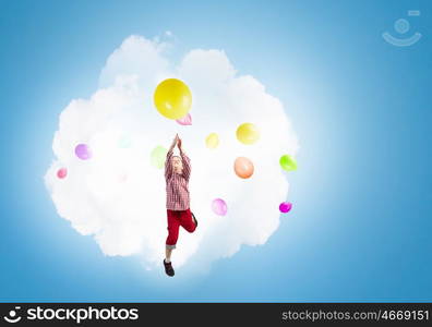 Happy careless childhood. Little happy cute boy flying on balloon