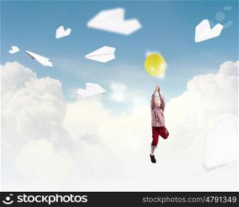 Happy careless childhood. Little happy cute boy flying on balloon