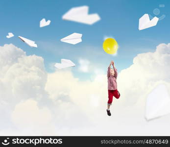 Happy careless childhood. Little happy cute boy flying on balloon