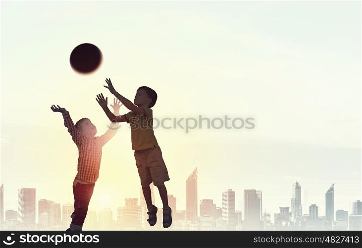 Happy careless childhood. Silhouettes of children jumping high joyfully on sunset background