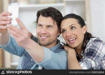 happy casual couple taking a selfie in living room