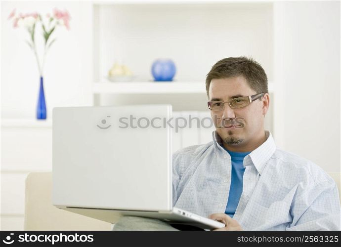 Happy casual man teleworking using laptop computer at home.