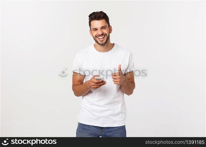 Happy casual man with smartphone and thumb up over gray background.. Happy casual man with smartphone and thumb up over gray background